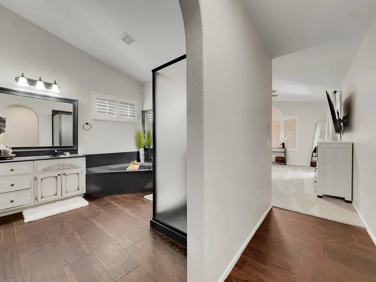 A tranquil bathroom scene featuring a spacious vanity with a large mirror, a luxurious bathtub, and a modern shower area. Soft lighting and clean lines create a spa-like, inviting environment for relaxation and self-care routines.