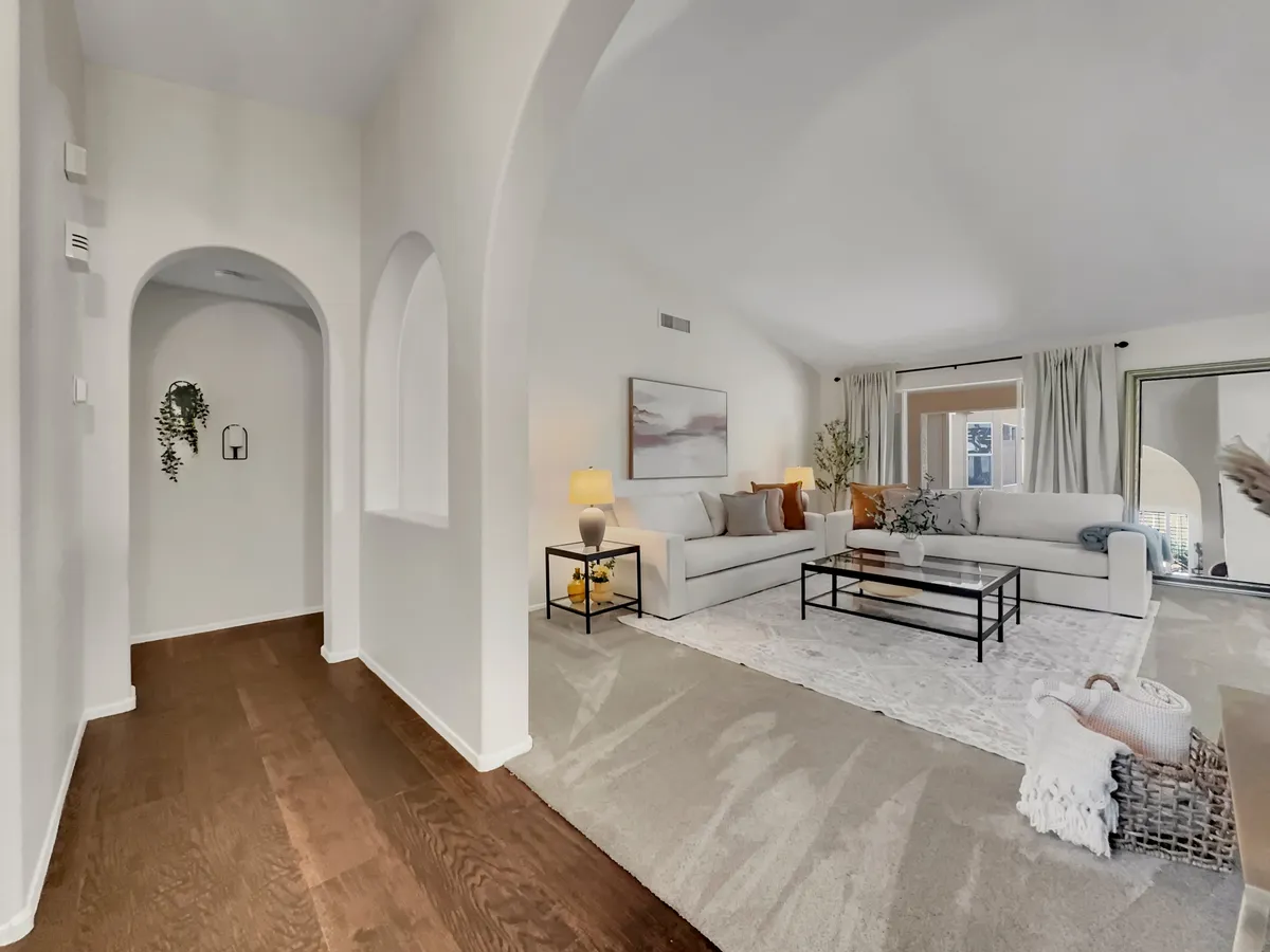 A welcoming living area that highlights a sofa set arranged around a coffee table on an area rug, accompanied by artwork and lush plants. The room features inviting lighting and a warm, homey feel, suggesting both social gatherings and quiet family moments.