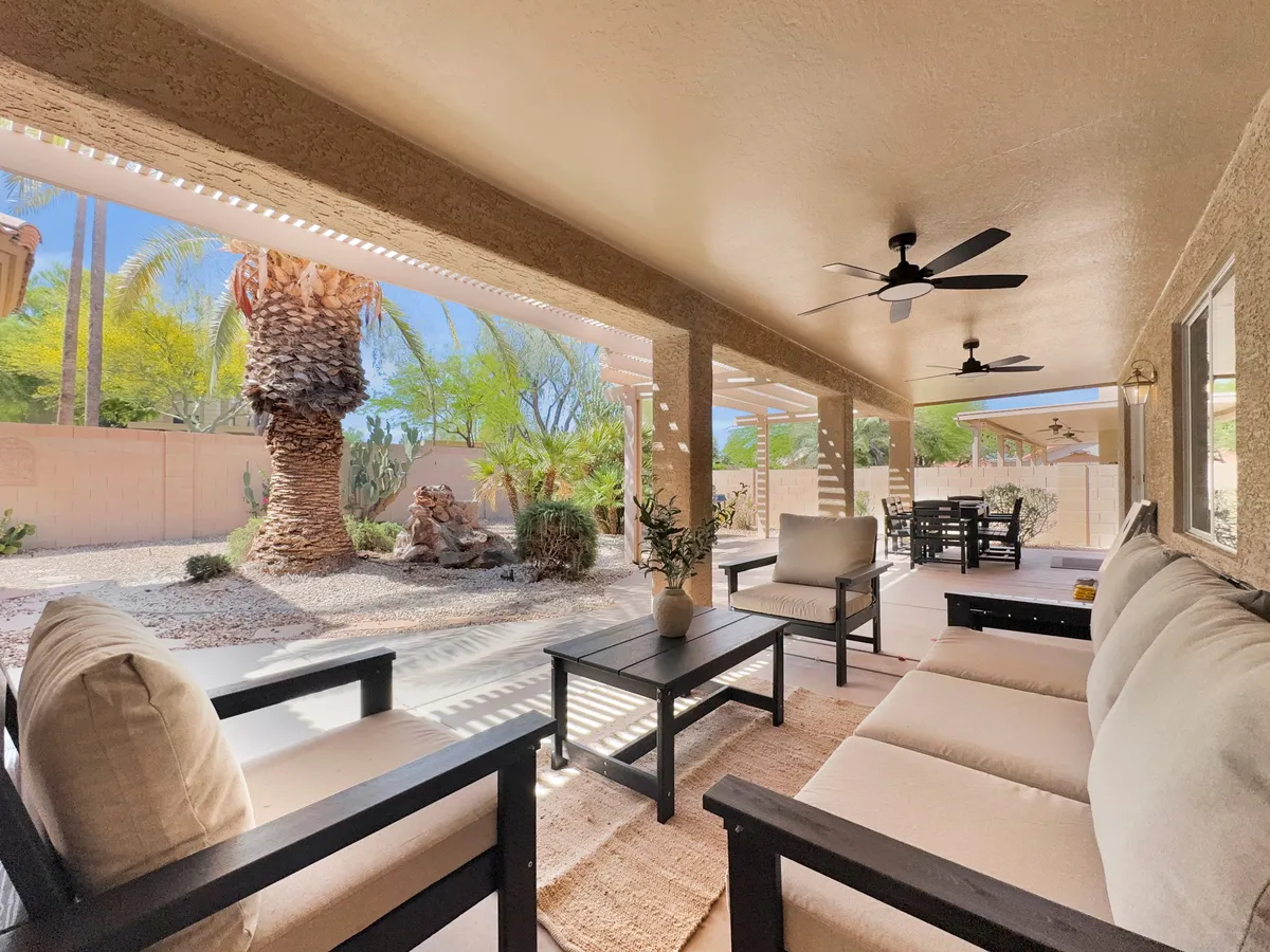 A beautifully designed outdoor seating area with a palm tree, decorative rocks, and a dining set. The space looks ideal for relaxing, entertaining, or enjoying meals outdoors, with a tranquil, welcoming ambiance.