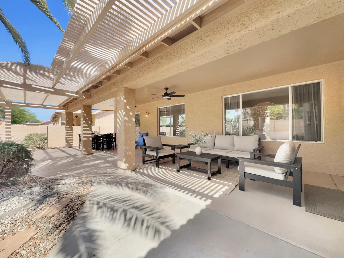A tranquil and stylish outdoor seating area under a shaded pergola adorned with decorative plants, perfect for conversation, relaxation, or intimate group celebrations.